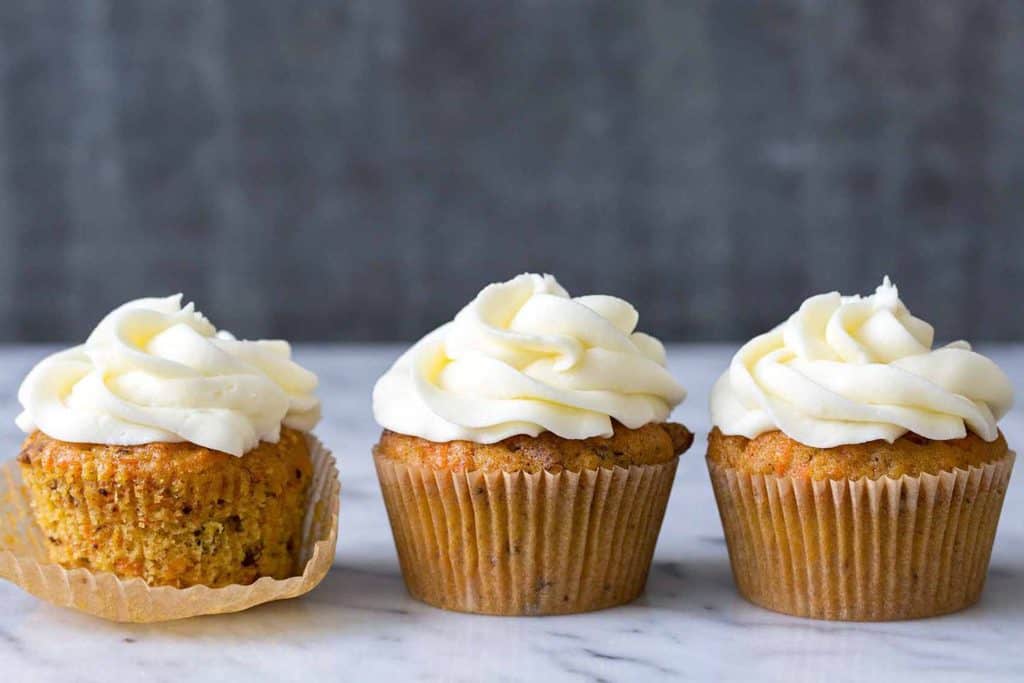Cream cheese frosting cupcakes on a marble surface with a dark background, showcasing delicious frosted cupcakes perfect for desserts or special occasions.