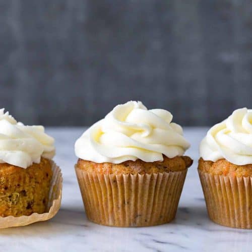 Cream cheese frosting cupcakes on a marble surface with a dark background, showcasing delicious frosted cupcakes perfect for desserts or special occasions.
