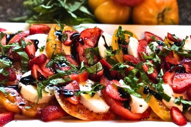 Fresh Caprese Salad with Strawberries, Basil, and Balsamic Glaze on a White Platter.