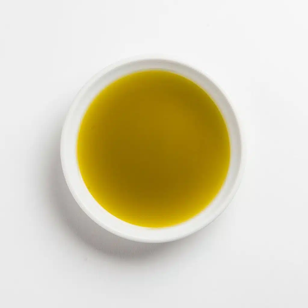 Smooth green olive oil in a white bowl, top view.