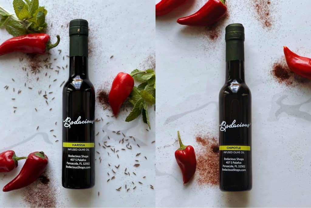 Rich infused olive oil bottles with fresh chili peppers, herbs, and spices, highlighting gourmet condiments from Bodacious Shops. Perfect for culinary enthusiasts seeking flavorful kitchen essentials.