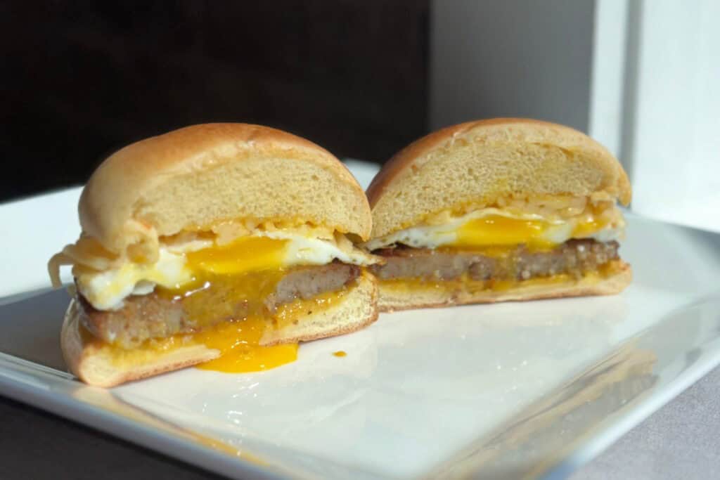 Delicious breakfast sandwich with fried egg, sausage patty, and melted cheese on a soft bun, perfect for a hearty start to your day.