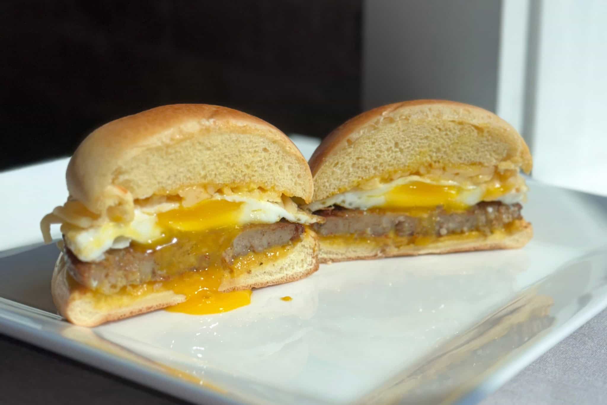 Delicious breakfast sandwich with fried egg, sausage patty, and melted cheese on a soft bun, perfect for a hearty start to your day.